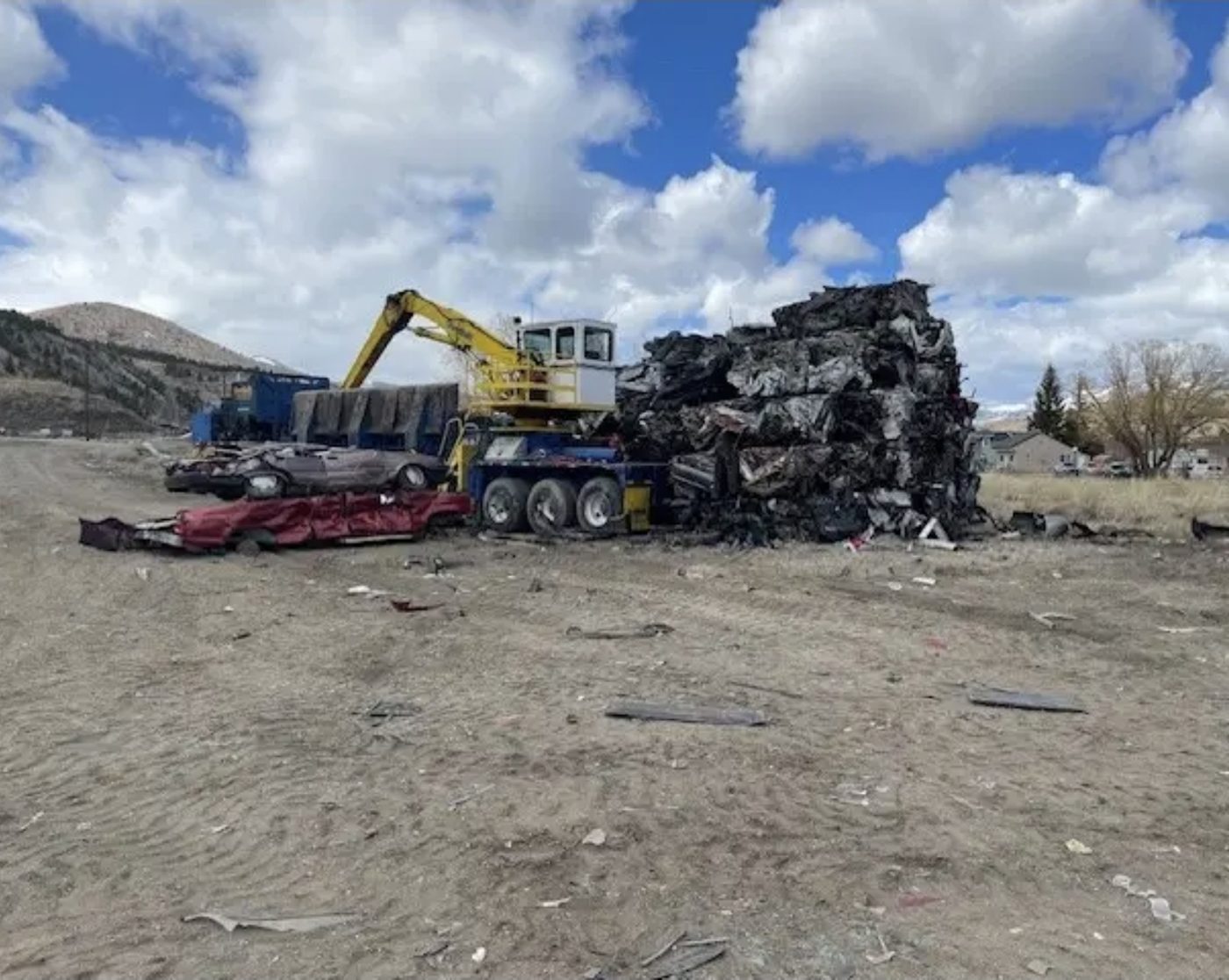 Car crusher loading flattened vehicles into stacks