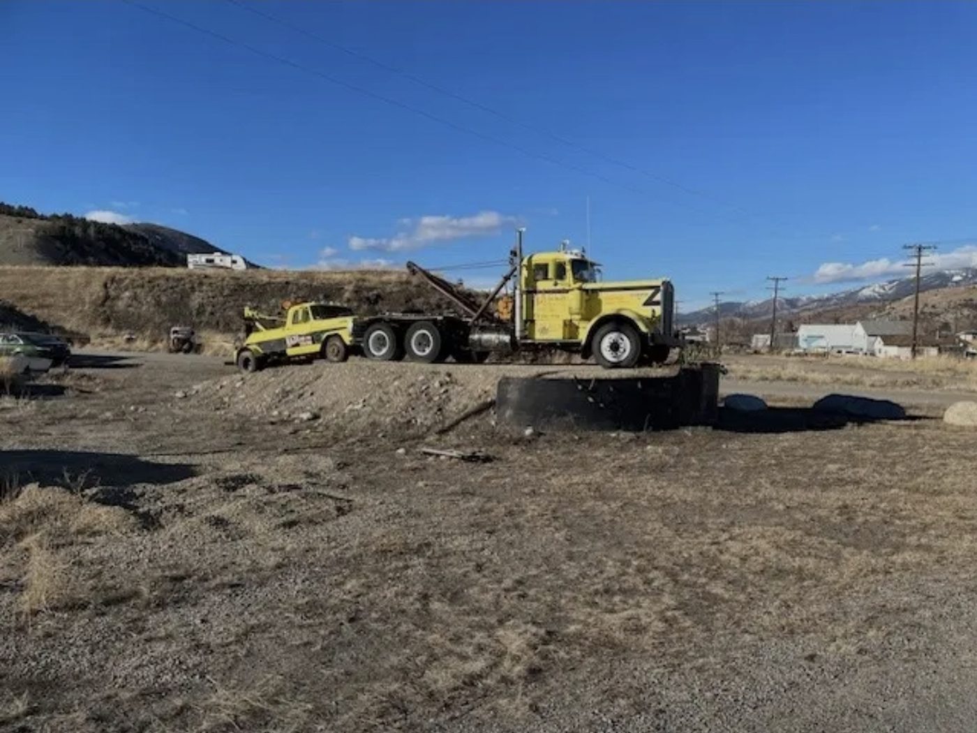 Yellow wrecker and heavy tow truck in the yard